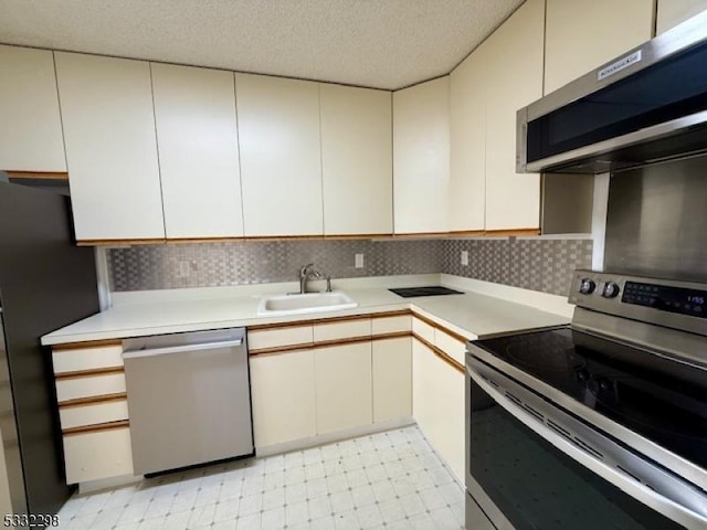 kitchen featuring sink, backsplash, a textured ceiling, and appliances with stainless steel finishes