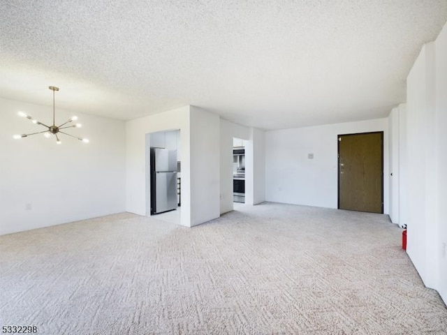 carpeted empty room with a chandelier and a textured ceiling