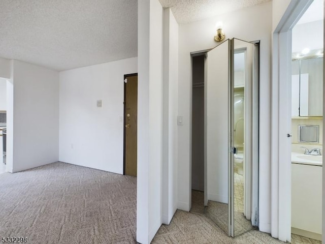 corridor featuring light colored carpet and a textured ceiling