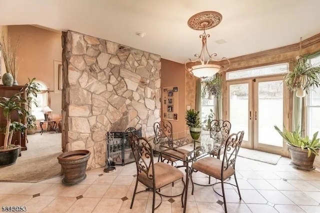 carpeted dining room featuring a stone fireplace and french doors