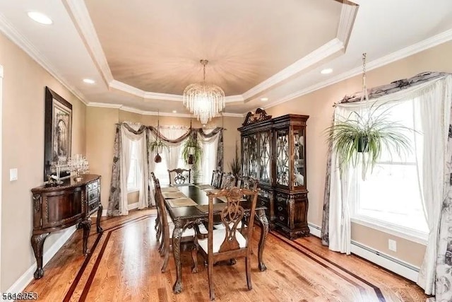 dining space with hardwood / wood-style floors, ornamental molding, baseboard heating, a tray ceiling, and a chandelier