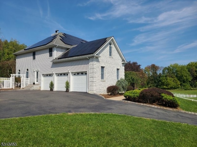 view of side of property featuring solar panels and a garage