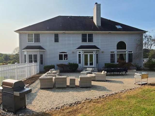 rear view of property featuring a patio area, an outdoor living space, and french doors