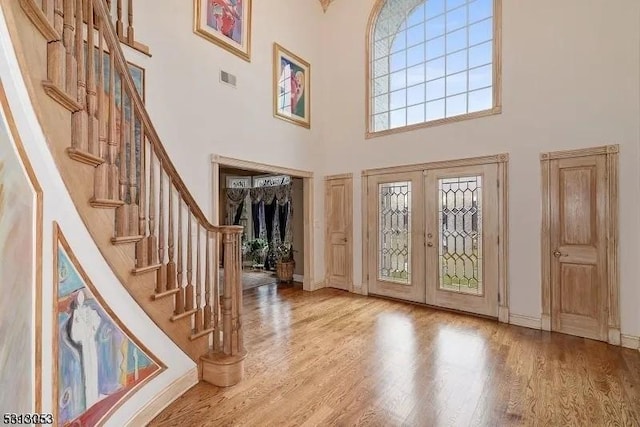 entryway featuring french doors, light hardwood / wood-style flooring, and a high ceiling