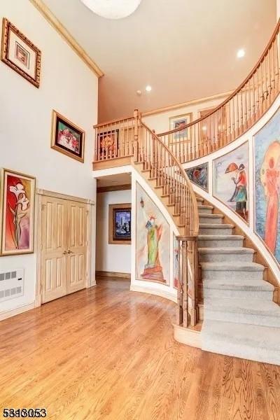 stairway featuring hardwood / wood-style floors, a high ceiling, and ornamental molding