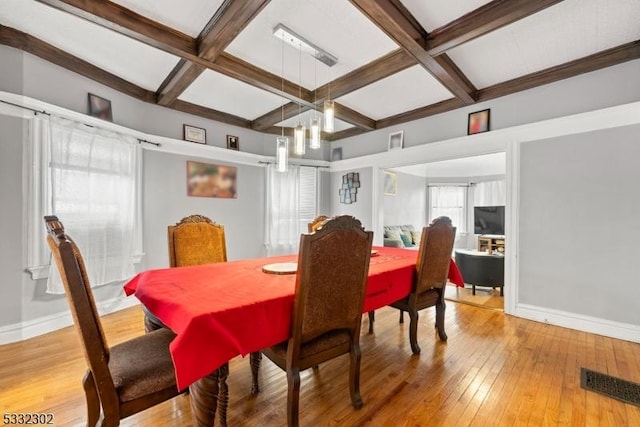 dining space featuring coffered ceiling, light wood-type flooring, and beam ceiling