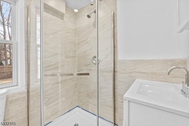 bathroom featuring vanity, walk in shower, and tile walls