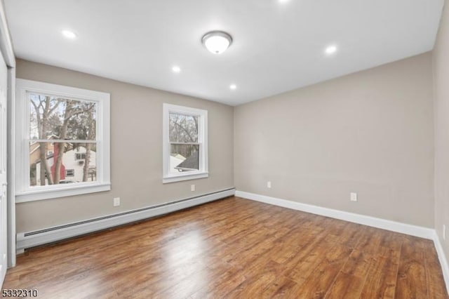 empty room with hardwood / wood-style floors and a baseboard heating unit