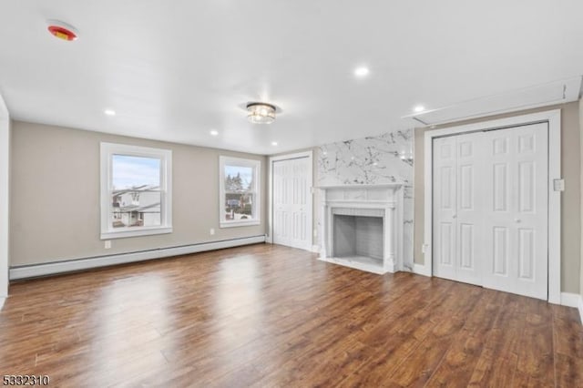 unfurnished living room with hardwood / wood-style flooring, a fireplace, and a baseboard heating unit