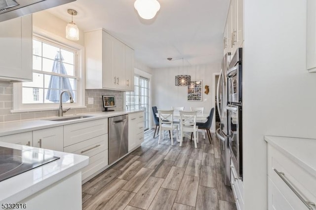 kitchen featuring white cabinetry, dishwasher, sink, and pendant lighting