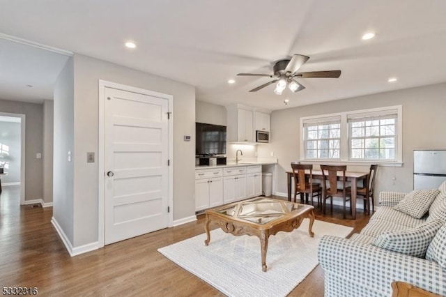 living room with sink, ceiling fan, and light hardwood / wood-style flooring