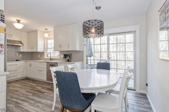 dining space featuring a healthy amount of sunlight, sink, and light hardwood / wood-style flooring