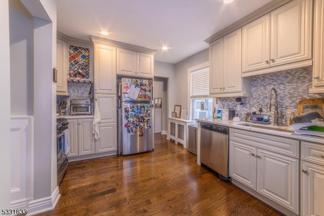 kitchen with decorative backsplash, stainless steel appliances, dark wood-type flooring, sink, and white cabinetry