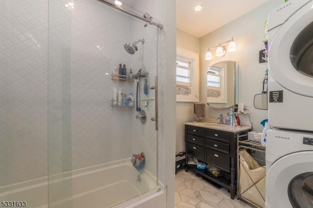 bathroom featuring tile patterned floors, stacked washer and dryer, vanity, and combined bath / shower with glass door