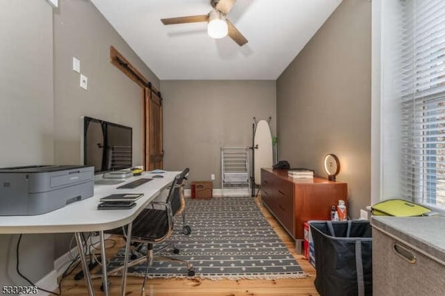 office with ceiling fan, wood-type flooring, and a barn door