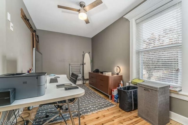 office space with hardwood / wood-style floors, a barn door, a wealth of natural light, and ceiling fan