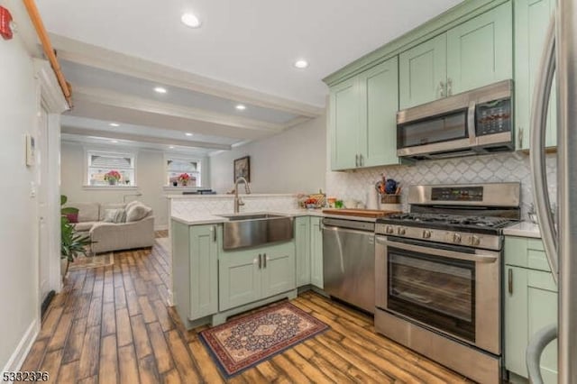 kitchen featuring sink, hardwood / wood-style flooring, green cabinets, kitchen peninsula, and stainless steel appliances