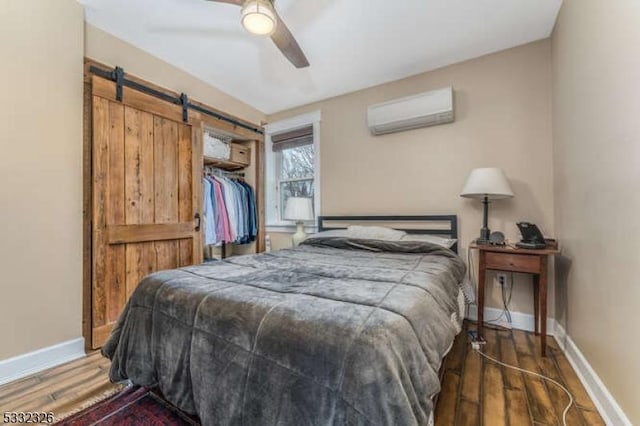 bedroom with a closet, a wall unit AC, dark hardwood / wood-style floors, and ceiling fan