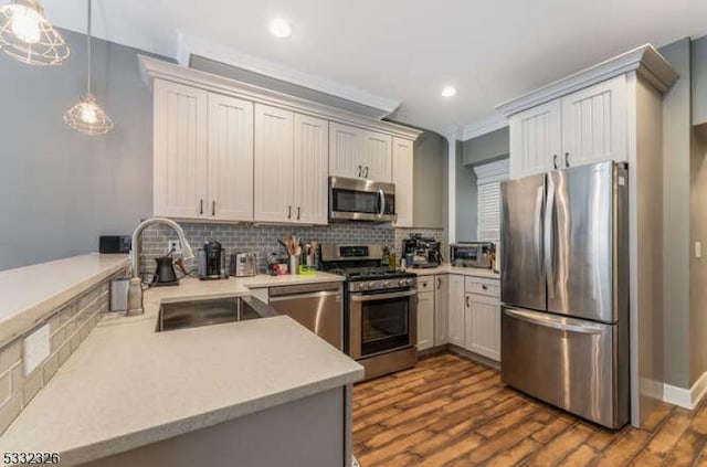 kitchen featuring appliances with stainless steel finishes, pendant lighting, sink, backsplash, and kitchen peninsula