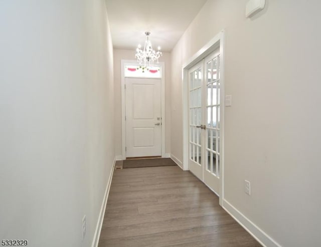 doorway with light hardwood / wood-style floors, french doors, and a notable chandelier