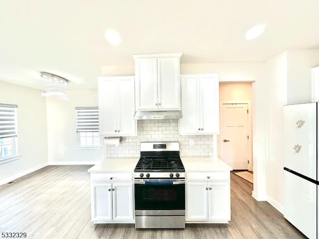 kitchen featuring range hood, backsplash, white cabinets, and stainless steel range with gas stovetop