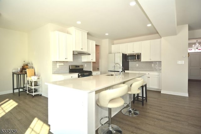 kitchen featuring white cabinetry, a breakfast bar area, appliances with stainless steel finishes, a kitchen island with sink, and sink