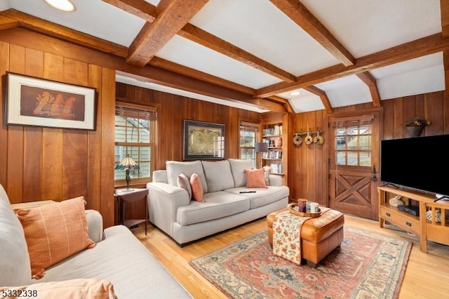 living room featuring beam ceiling, light hardwood / wood-style flooring, coffered ceiling, and wooden walls