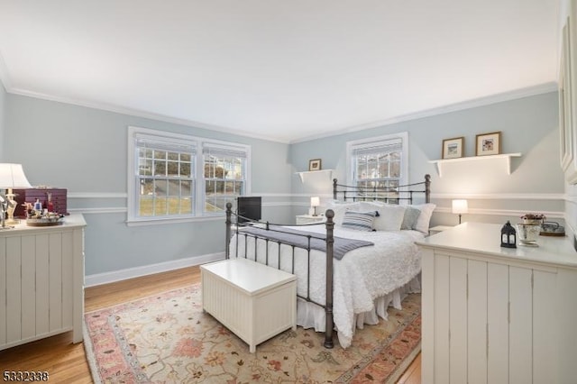 bedroom with multiple windows, ornamental molding, and light wood-type flooring