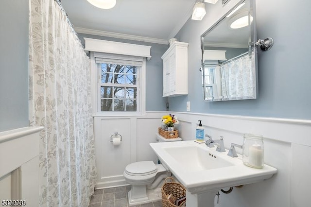 bathroom with toilet, crown molding, and plenty of natural light