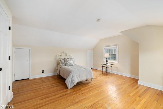 bedroom with light wood-type flooring and vaulted ceiling