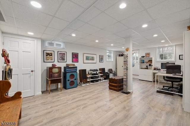 office area featuring a healthy amount of sunlight, a paneled ceiling, and light wood-type flooring