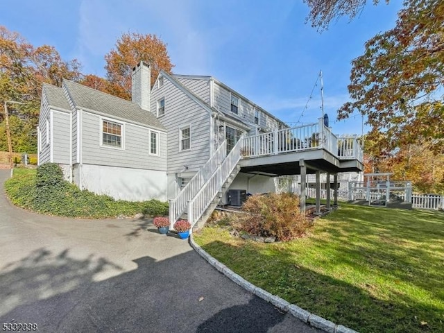 view of home's exterior with a lawn, central AC, and a deck