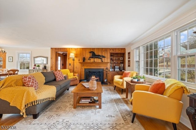 living room with built in shelves, wooden walls, and a chandelier