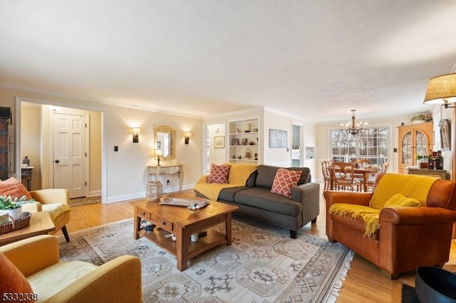 living room with light hardwood / wood-style floors, ornamental molding, built in features, and a chandelier