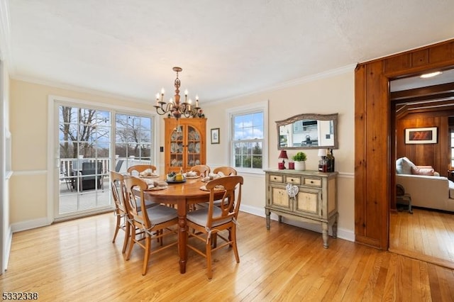 dining room with an inviting chandelier, ornamental molding, and light hardwood / wood-style flooring