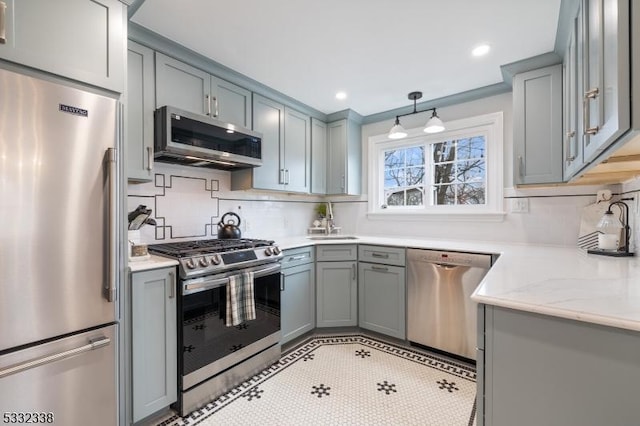 kitchen with sink, light stone counters, light tile patterned floors, hanging light fixtures, and appliances with stainless steel finishes