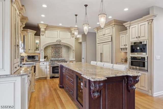 kitchen featuring pendant lighting, light hardwood / wood-style flooring, backsplash, a kitchen island, and premium appliances