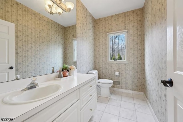 bathroom with toilet, tile patterned flooring, vanity, and an inviting chandelier