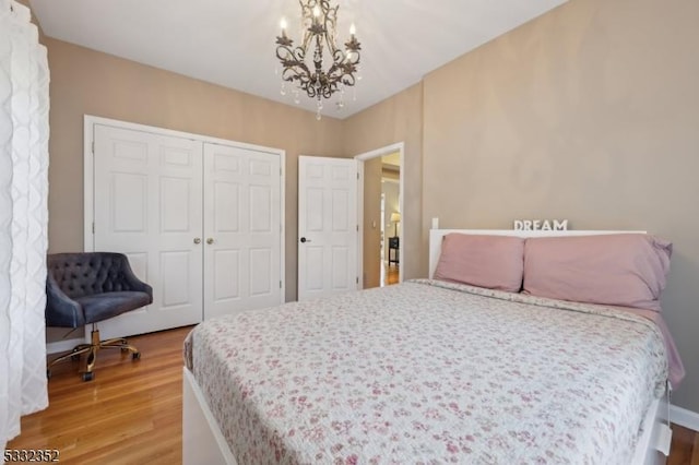 bedroom with wood-type flooring, a notable chandelier, and a closet