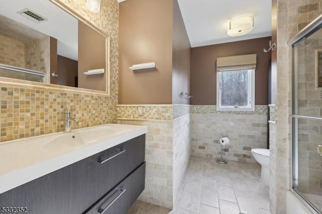 full bathroom featuring tile walls, tile patterned flooring, toilet, and vanity