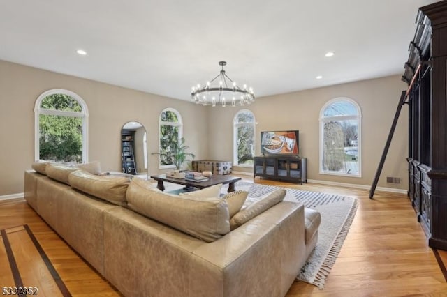 living room with light hardwood / wood-style floors, a healthy amount of sunlight, and a notable chandelier