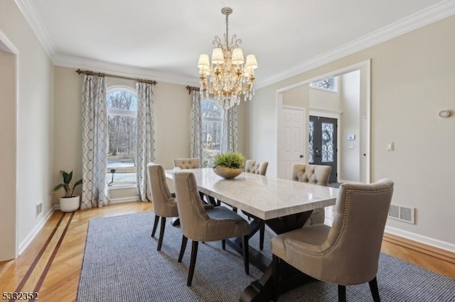 dining space with light hardwood / wood-style flooring, an inviting chandelier, and crown molding