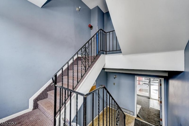 stairway featuring a towering ceiling and baseboards