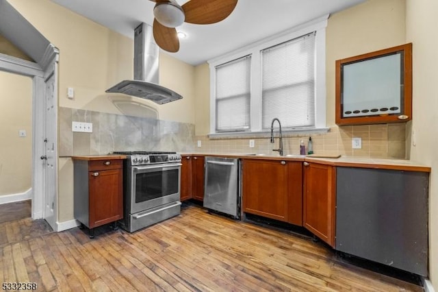 kitchen featuring ceiling fan, ventilation hood, stainless steel appliances, and light hardwood / wood-style floors