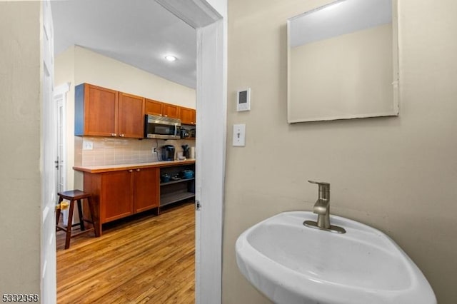 bathroom with decorative backsplash, sink, and hardwood / wood-style flooring