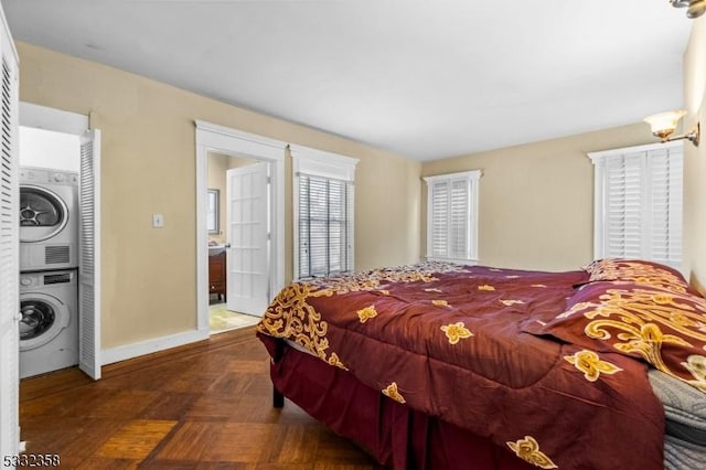 bedroom featuring ensuite bathroom, stacked washer / dryer, and dark parquet flooring