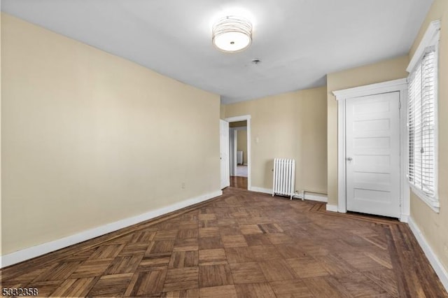 unfurnished bedroom with dark parquet flooring and radiator heating unit