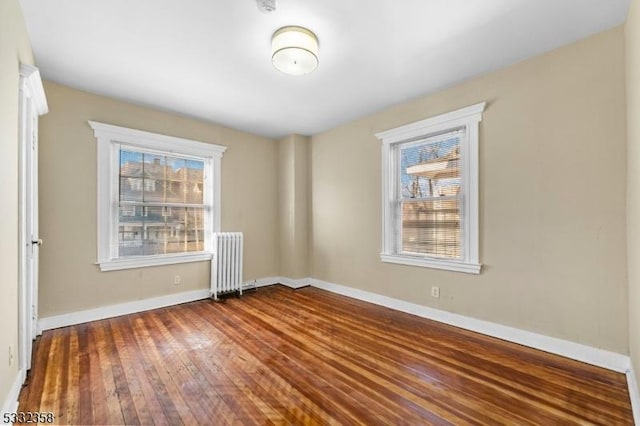 spare room featuring wood-type flooring and radiator heating unit