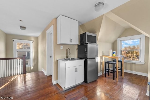 kitchen with dark wood-type flooring, sink, white cabinetry, and stainless steel fridge