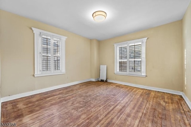 unfurnished room featuring hardwood / wood-style flooring, plenty of natural light, and radiator heating unit